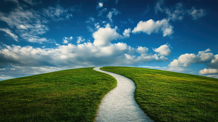 Green land with pathway and blue sky with clouds